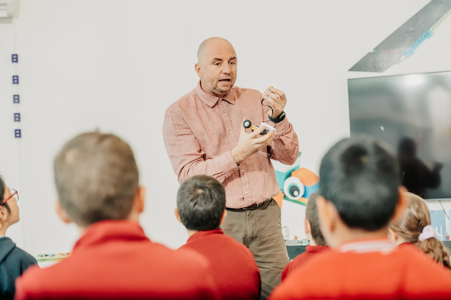 A mentor demonstrating a robot to a group of children